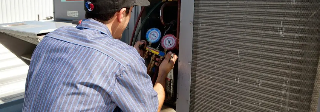 HVAC technician servicing a condenser unit in Maplewood